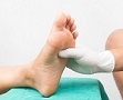 Image of a gloved hand holding patient's foot on medical bed