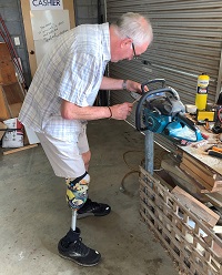 Image of a man with a prosthetic leg using machinery to engage in craft work