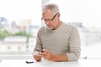 Image of a middle aged man with glasses checking insulin levels with a handheld device
