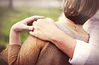 Image of a woman receiving a supportive embrace from a peer