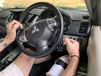 Image of man with prosthetic leg in the cockpit driving a car