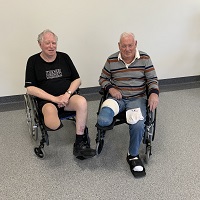 Image of two middle aged men with lower limb loss in wheelchairs presenting for photo