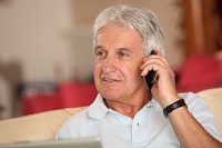 Middle aged man sitting on a couch speaking on a mobile phone